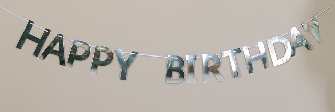 A photo of a string banner with shiny individual letters hanging on it spelling "HAPPY BIRTHDAY"